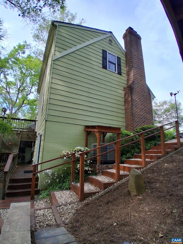 view of home's exterior with stairway, a wooden deck, and a chimney