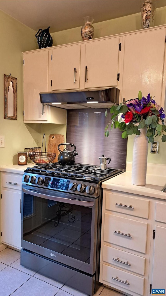 kitchen featuring stainless steel gas range oven, light tile patterned flooring, under cabinet range hood, and light countertops