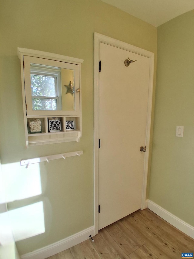 hall featuring light wood-style flooring and baseboards