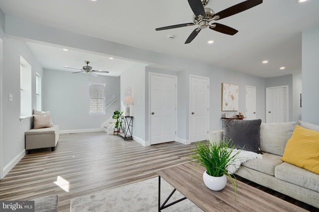 living room featuring baseboards, wood finished floors, recessed lighting, a ceiling fan, and stairs