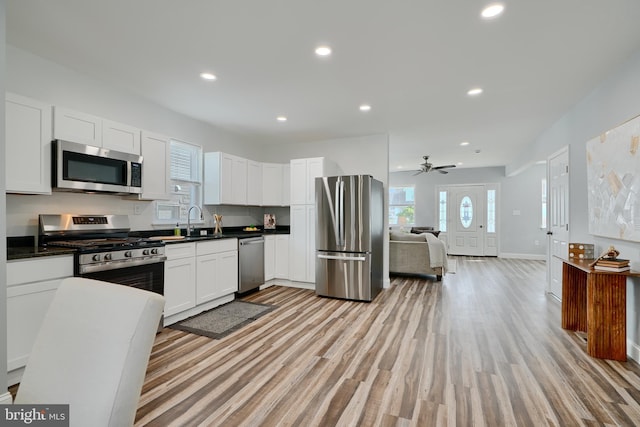 kitchen featuring stainless steel appliances, dark countertops, light wood finished floors, recessed lighting, and white cabinets