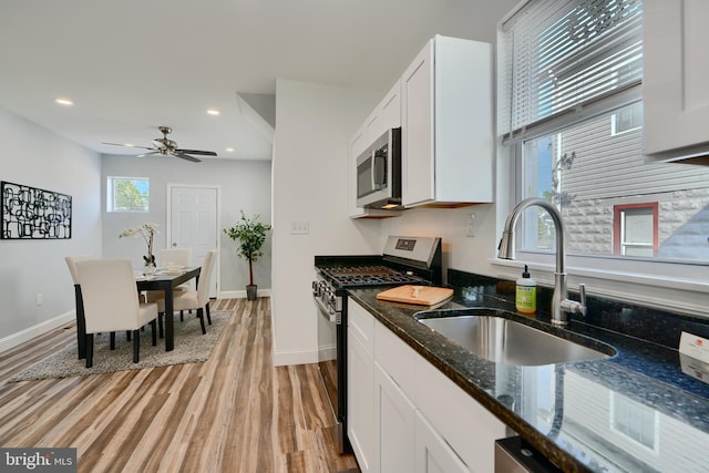 kitchen with stainless steel appliances, a sink, light wood finished floors, white cabinetry, and recessed lighting