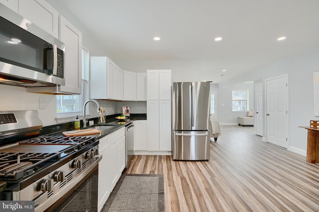 kitchen featuring appliances with stainless steel finishes, a sink, plenty of natural light, light wood-type flooring, and recessed lighting