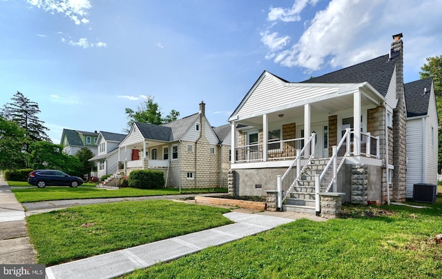 view of front of home featuring a porch, a front lawn, stairway, roof with shingles, and a chimney