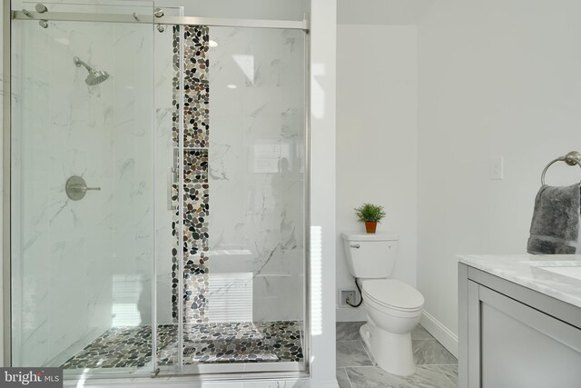 bathroom featuring a marble finish shower, toilet, baseboards, marble look tile flooring, and vanity