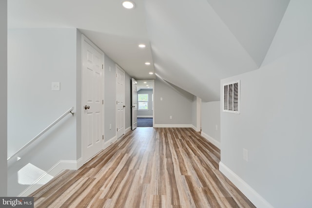additional living space with light wood-style flooring, recessed lighting, baseboards, and lofted ceiling