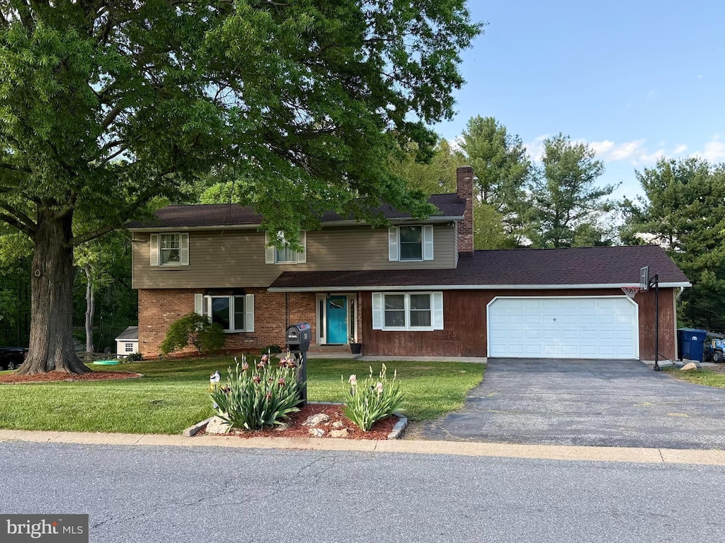 traditional home featuring a chimney, an attached garage, asphalt driveway, and a front lawn