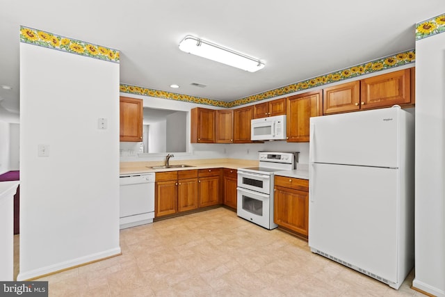 kitchen featuring white appliances, a sink, brown cabinetry, light countertops, and light flooring