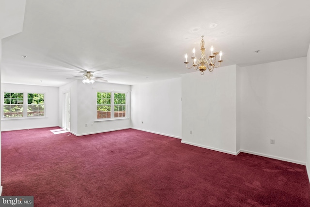 empty room featuring a chandelier, dark colored carpet, baseboards, and a ceiling fan