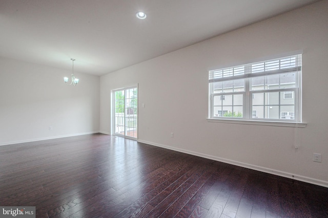 empty room with a chandelier, dark wood-type flooring, baseboards, and recessed lighting