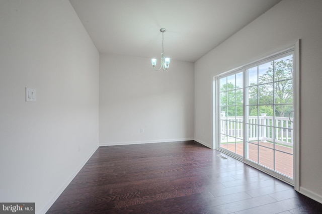 empty room with dark wood-style flooring, a chandelier, and baseboards