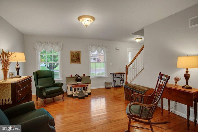 living area with light wood-style floors, stairs, and baseboards