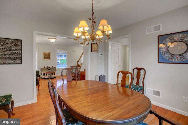 dining area with a chandelier, light wood-style flooring, baseboards, and stairway