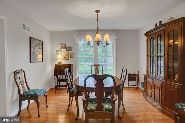 dining room featuring a chandelier, light wood-type flooring, and baseboards