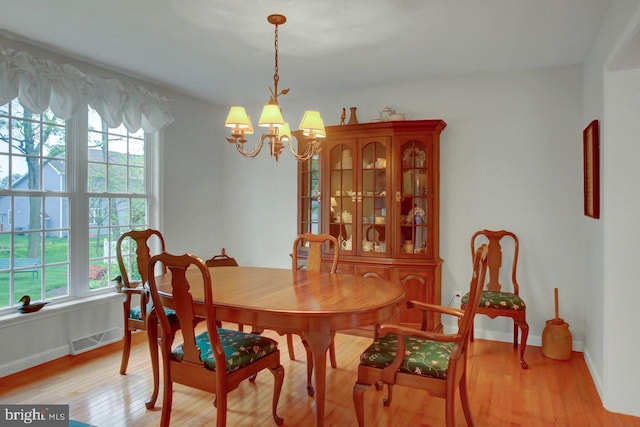 dining space featuring plenty of natural light, a chandelier, baseboards, and light wood finished floors