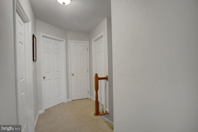 corridor featuring an upstairs landing, baseboards, and light colored carpet