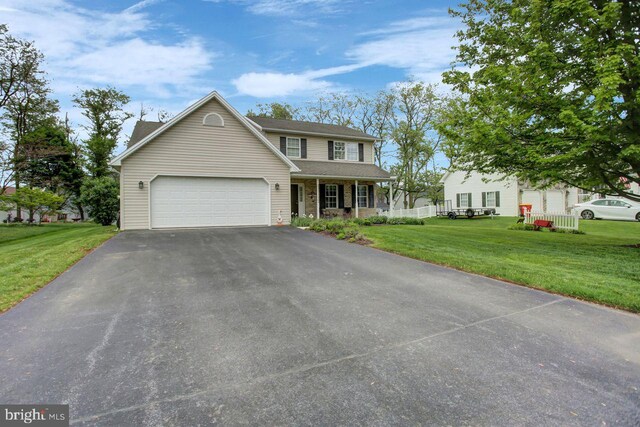 view of front of house featuring covered porch, a garage, driveway, and a front yard
