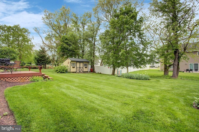 view of yard with a wooden deck, an outdoor structure, and a storage unit