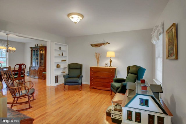 sitting room with light wood-style floors, a chandelier, and baseboards