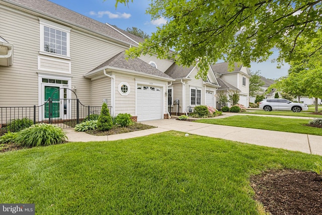 view of front of home featuring an attached garage, concrete driveway, a front lawn, and a shingled roof