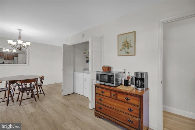 dining room with a chandelier, washer and dryer, light wood-style flooring, and baseboards