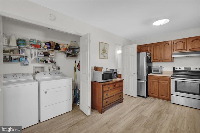 kitchen featuring stainless steel appliances, under cabinet range hood, washer and dryer, brown cabinets, and light wood-style floors