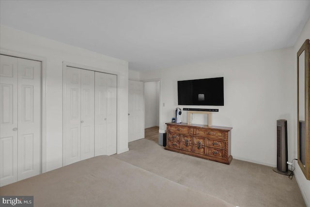 bedroom with carpet floors, two closets, and baseboards