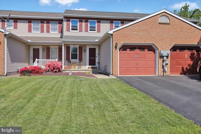 view of front facade with a porch, asphalt driveway, brick siding, an attached garage, and a front lawn
