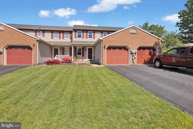 view of front of home featuring an attached garage, driveway, covered porch, and a front lawn