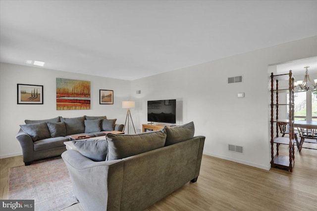 living room featuring a chandelier, baseboards, and wood finished floors