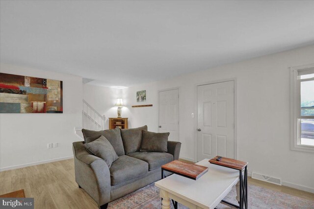 living room featuring stairs, light wood finished floors, and baseboards