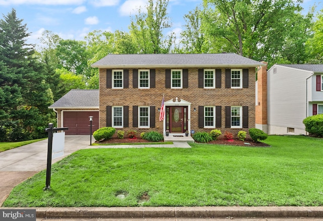 colonial house with concrete driveway, a front lawn, an attached garage, and brick siding