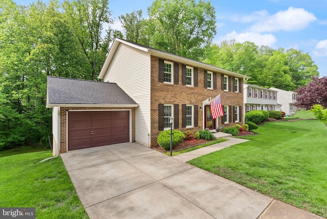 colonial-style house featuring concrete driveway, a garage, a front yard, and brick siding