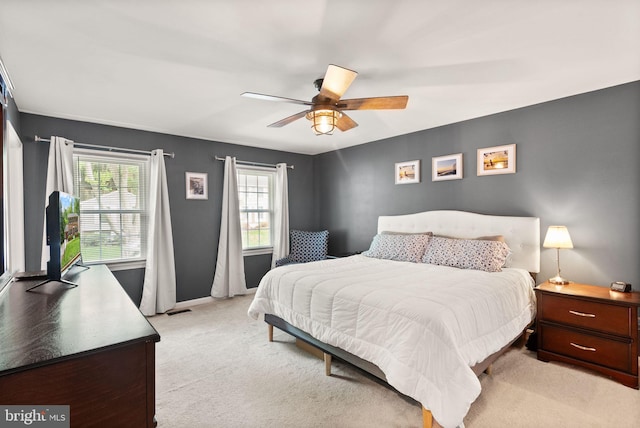 bedroom with light carpet, ceiling fan, and baseboards