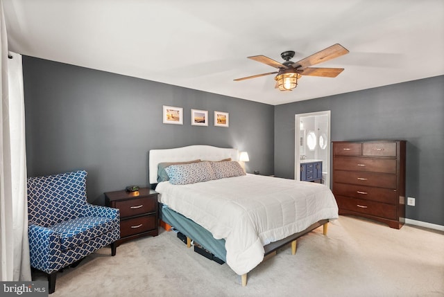 bedroom with light colored carpet, ensuite bath, and a ceiling fan