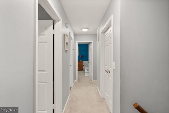 hallway with light colored carpet and baseboards