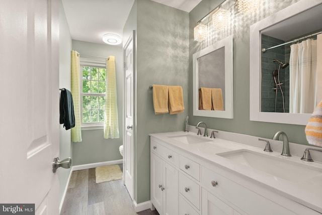 full bath with wood finished floors, baseboards, double vanity, and toilet