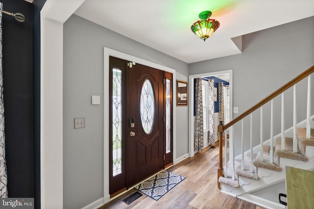 foyer entrance with stairway, wood finished floors, and baseboards