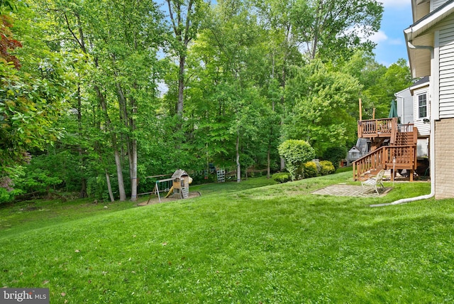 view of green lawn featuring stairway, a deck, and view of scattered trees
