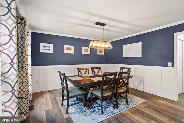 dining area with dark wood-style floors, crown molding, a decorative wall, and wainscoting