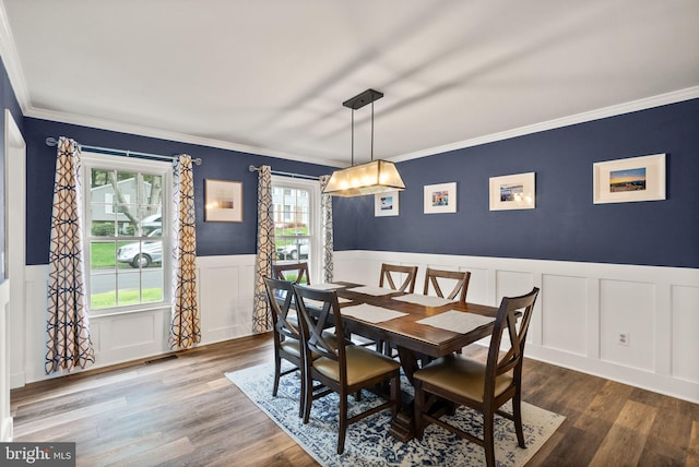 dining space with wainscoting, a decorative wall, plenty of natural light, ornamental molding, and wood finished floors