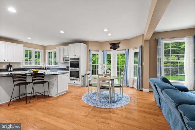 10701 Monocacy Way, Manassas, VA 20112 - kitchen with stainless steel appliances, tasteful backsplash, dark countertops, white cabinets, and a kitchen bar