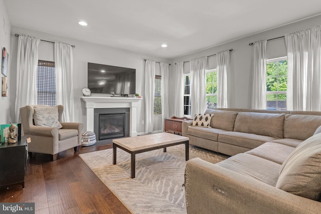 living room with dark wood-style floors, a fireplace with flush hearth, and recessed lighting