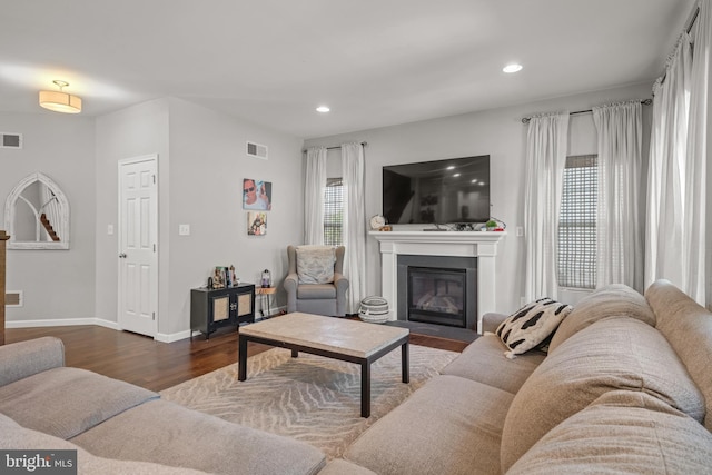 living area featuring a fireplace with flush hearth, wood finished floors, recessed lighting, and baseboards