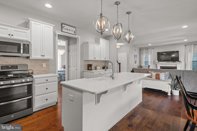 kitchen featuring stainless steel appliances, a chandelier, a sink, open floor plan, and tasteful backsplash