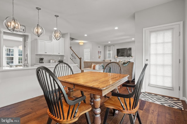 dining room featuring dark wood-style flooring, recessed lighting, stairs, and a chandelier
