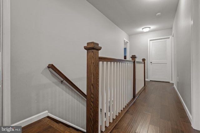 corridor featuring an upstairs landing, dark wood finished floors, and baseboards