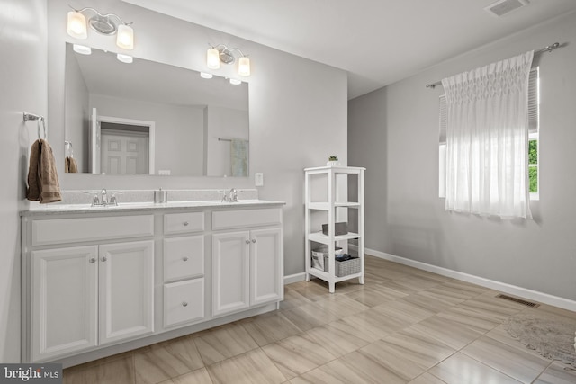 bathroom with baseboards, double vanity, and tile patterned floors