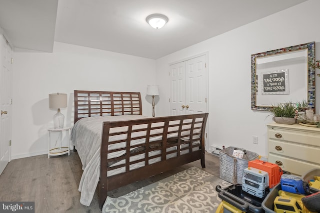 bedroom featuring wood finished floors, a closet, and baseboards