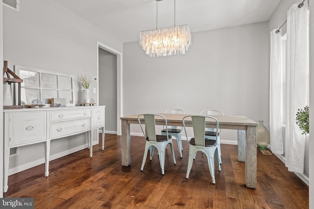 dining room with a chandelier, dark wood finished floors, and baseboards